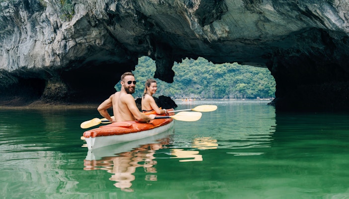 Couple kayaking among limestone karsts in Halong Bay, Vietnam.