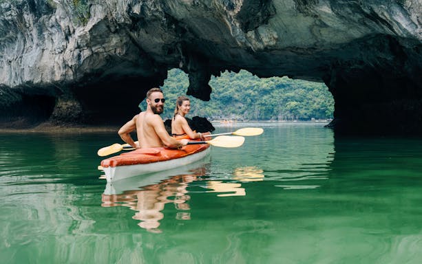 Couple kayaking through limestone karsts in Halong Bay, Vietnam.