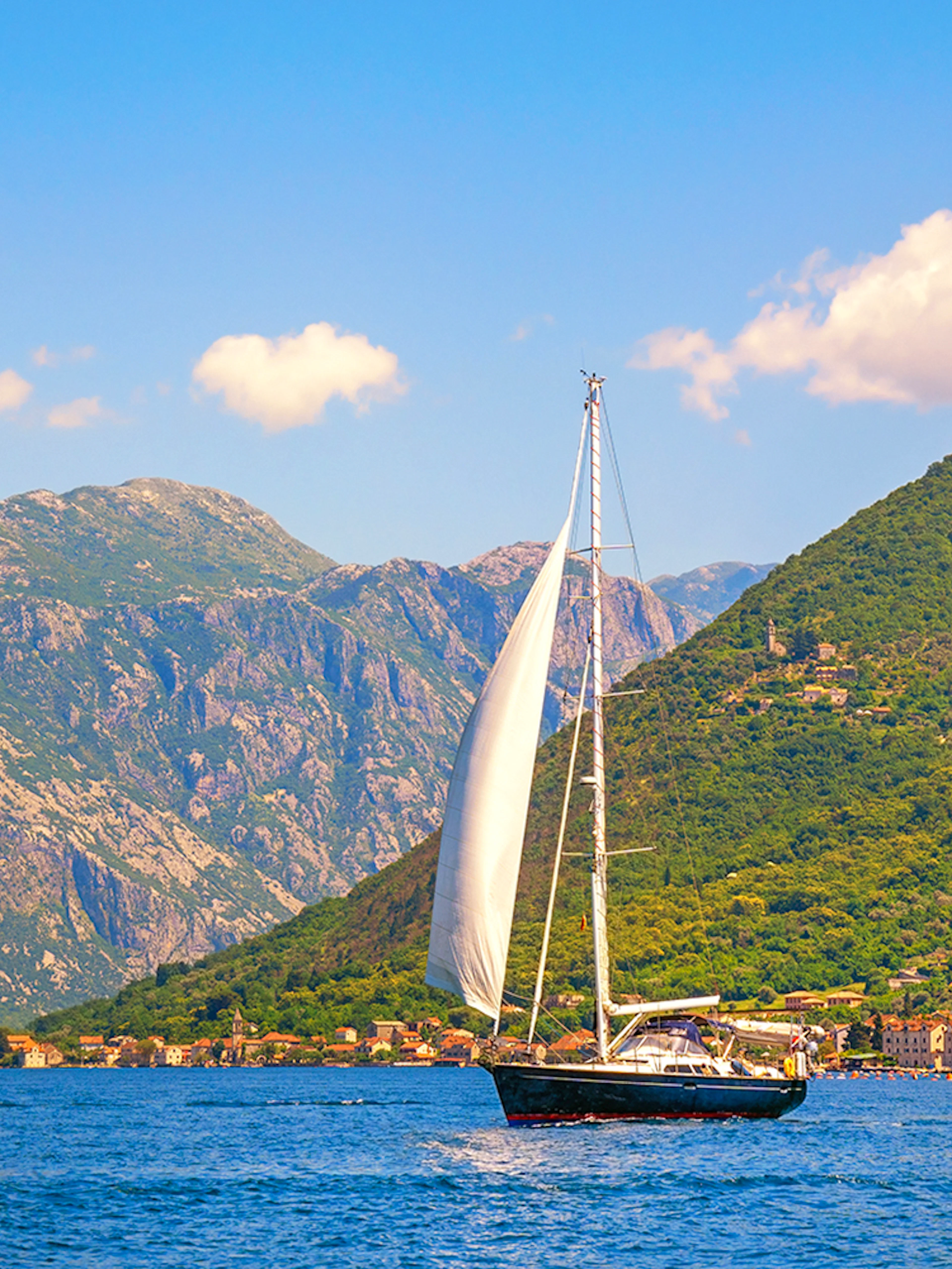 Catamaran sailing near coastal mountains on a full day cruise.