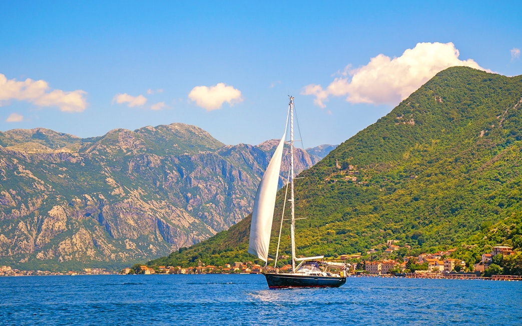 Catamaran sailing near coastal mountains on a full day cruise.