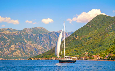 Catamaran sailing near coastal mountains on a full day cruise.