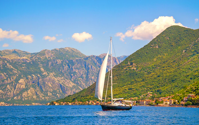Catamaran sailing near coastal mountains on a full day cruise.