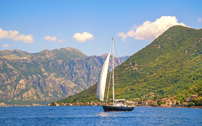 Catamaran sailing near coastal mountains on a full day cruise.