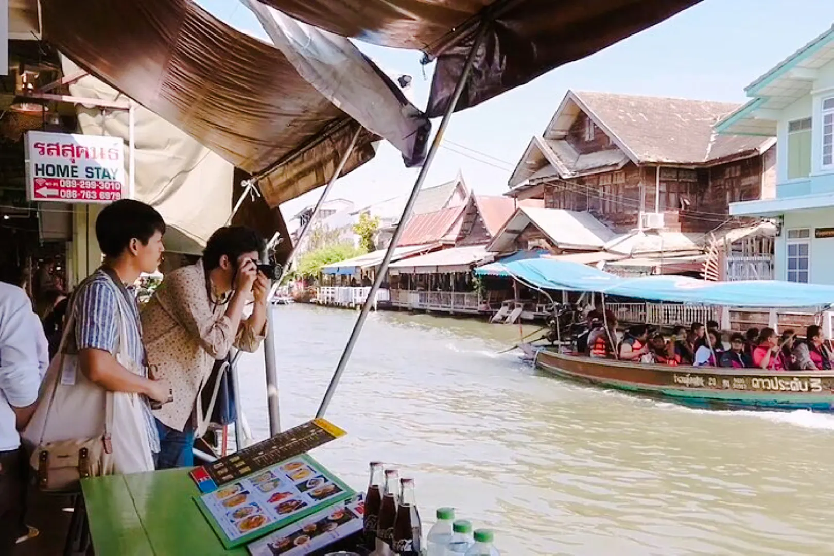 Tourists photographing boats at Amphawa Floating Markets during a private tour from Laem Chabang, Pattaya.