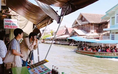 Tourists photographing boats at Amphawa Floating Markets during a private tour from Laem Chabang, Pattaya.