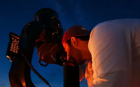 Guests stargazing through a telescope under a clear night sky.