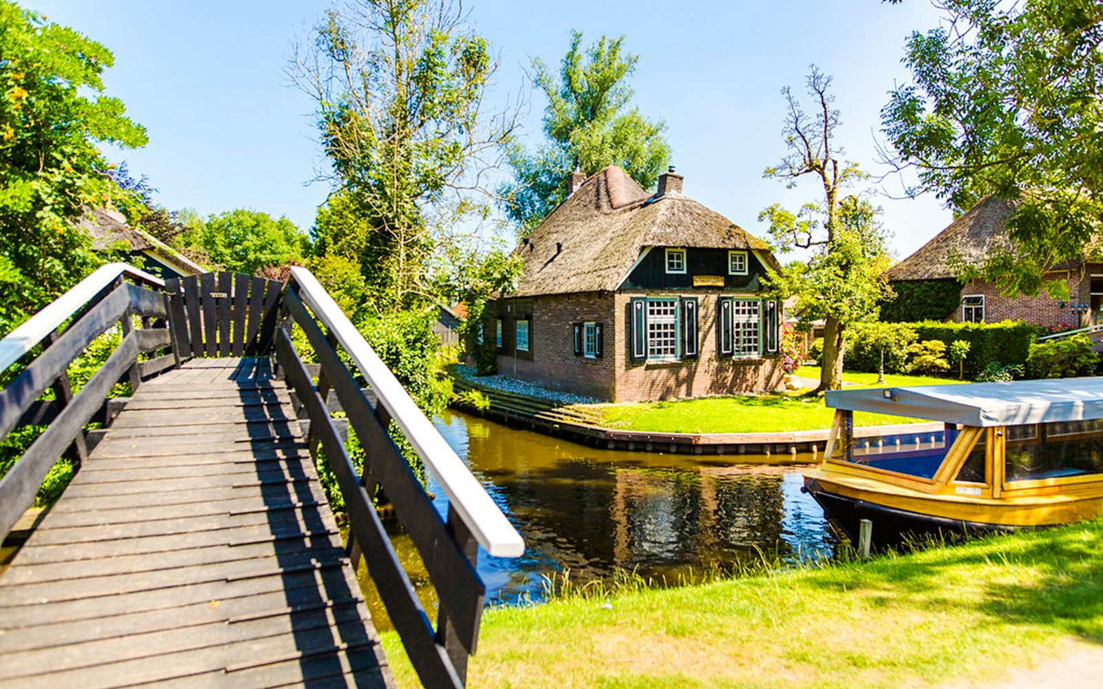 Giethoorn canal with boat and traditional thatched house.