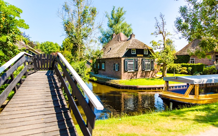 Giethoorn canal with boat and traditional thatched house.
