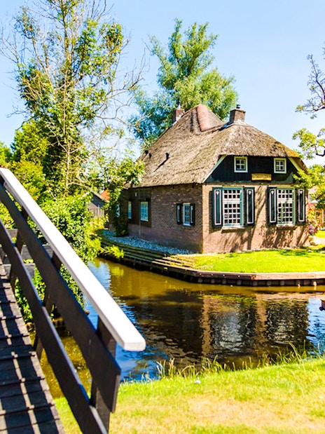 Giethoorn canal with boat and traditional thatched house.