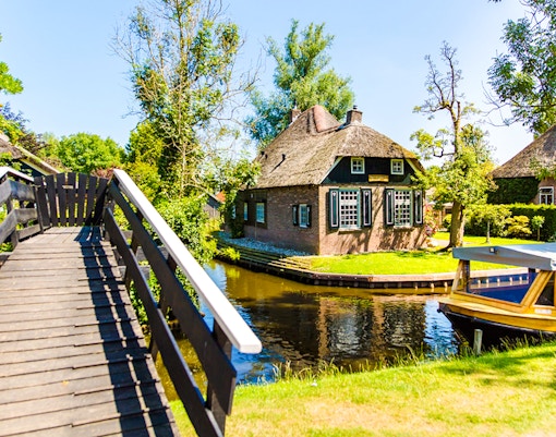 Giethoorn canal with boat and traditional thatched house.