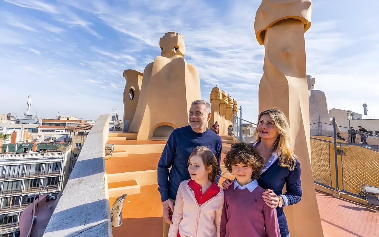 Family exploring rooftop of La Pedrera, Barcelona during guided tour.