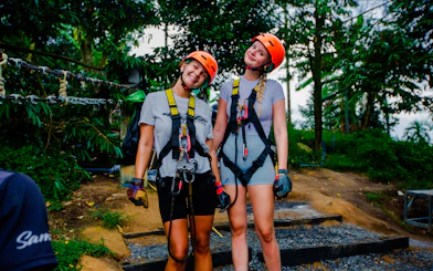 Two people in harnesses ready for ziplining at Tree Bridge Zipline, Koh Samui.