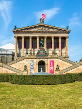 Front view of the Neues Museum in Berlin with statues and banners.