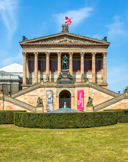 Front view of the Neues Museum in Berlin with statues and banners.