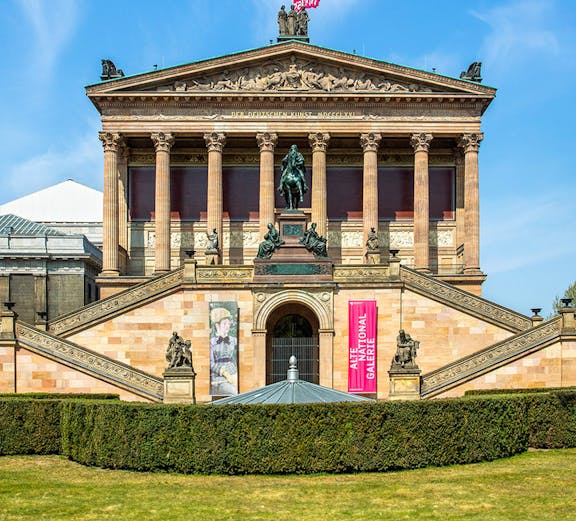 Front view of the Neues Museum in Berlin with statues and banners.