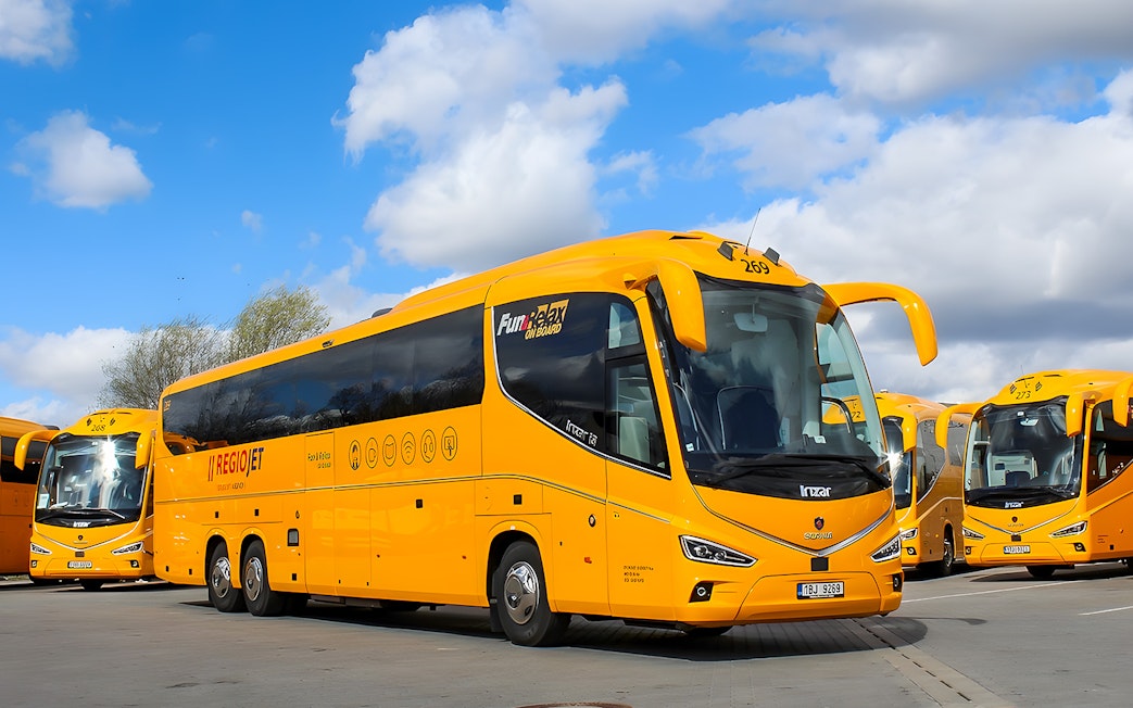 RegioJet bus parked in Prague under a blue sky.