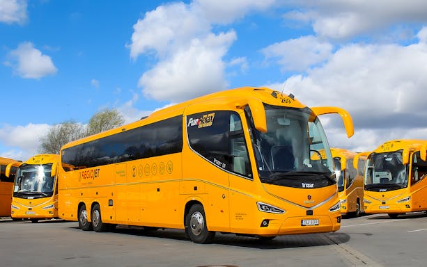 RegioJet bus parked in Prague under a blue sky.