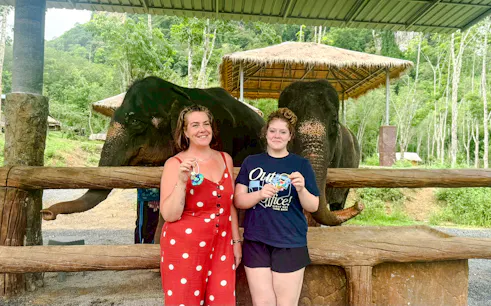 Visitors holding crafts with elephants at Krabi Elephant Local Project, Thailand.