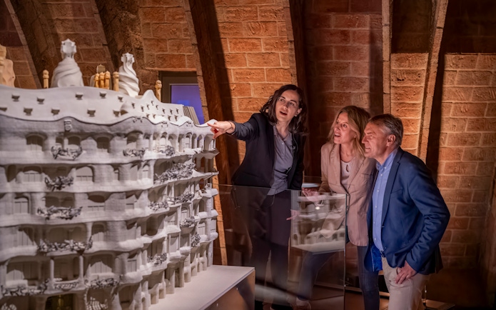 Tourist with guide examining Casa Mila model in Barcelona museum.
