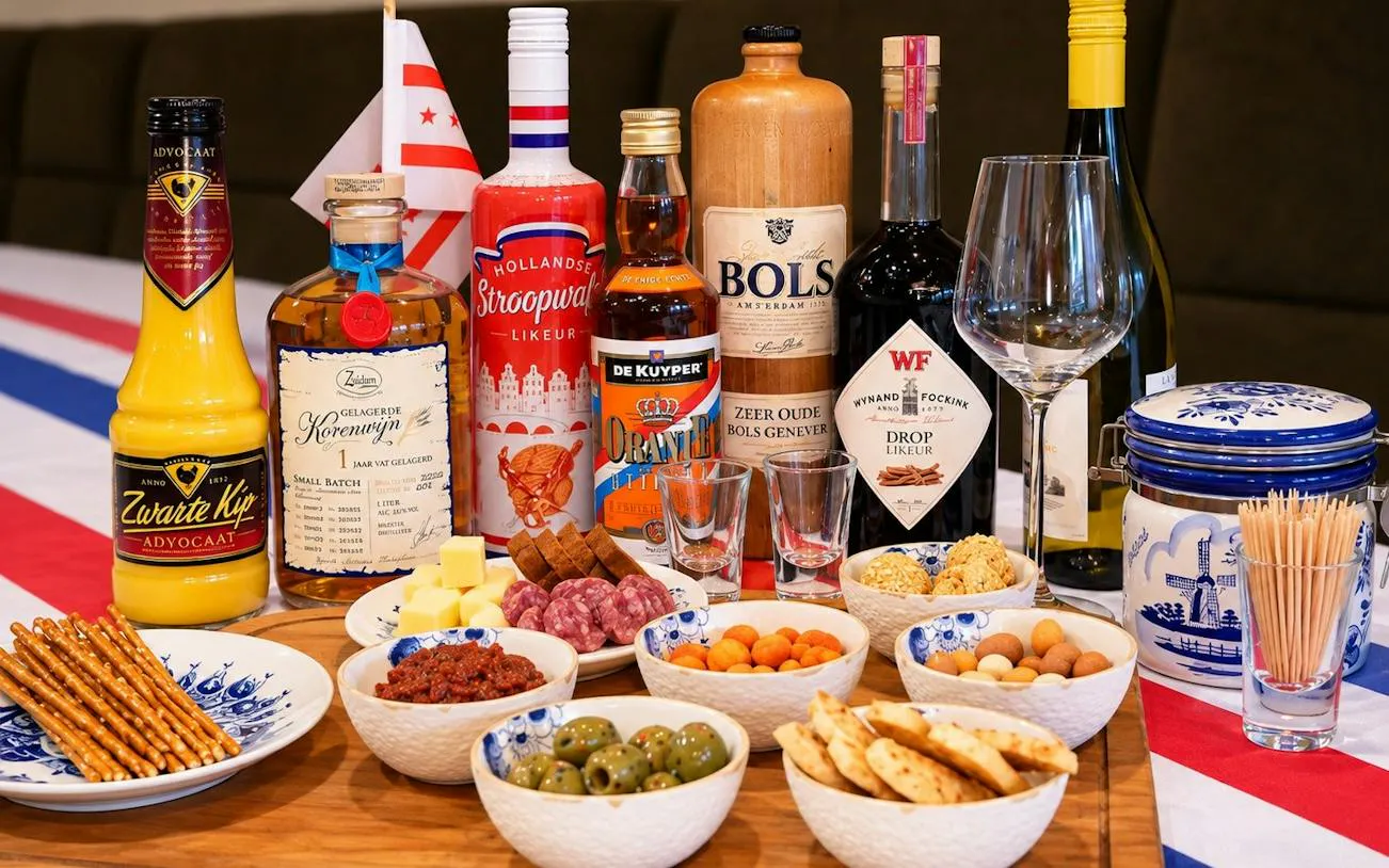 Traditional Dutch drinks and snacks display with liqueurs, cheese, olives, and pretzels in Amsterdam.