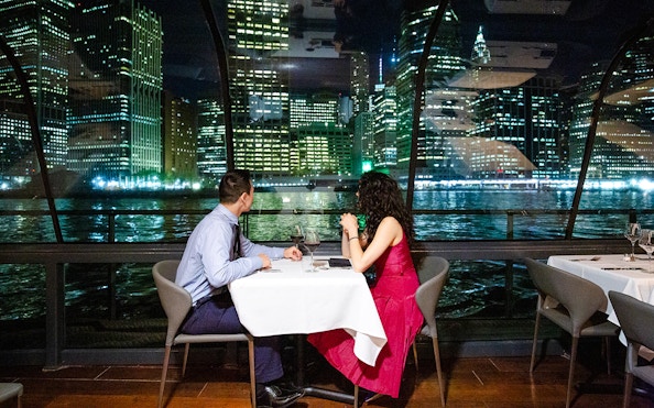 Couple dining on New Jersey Signature Cruise with city skyline view.