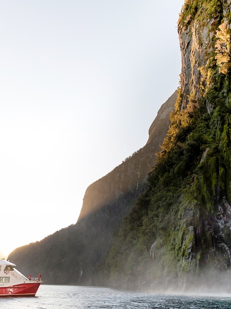 Cruise boat near waterfall in Milford Sound, New Zealand.