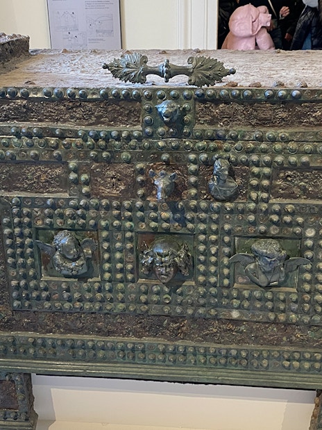 Ancient bronze chest with decorative reliefs at Naples National Archaeological Museum.