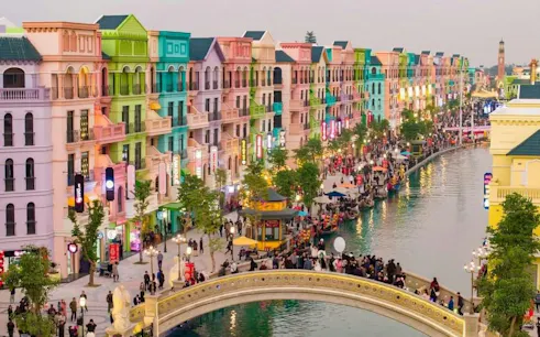 Colorful buildings along a canal with gondolas and a bridge in Dubai.
