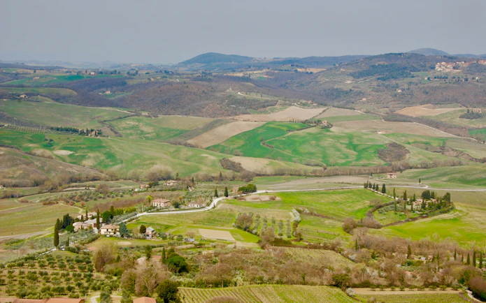 Rolling hills and vineyards in Tuscany, Italy, viewed from a distance on a clear day.