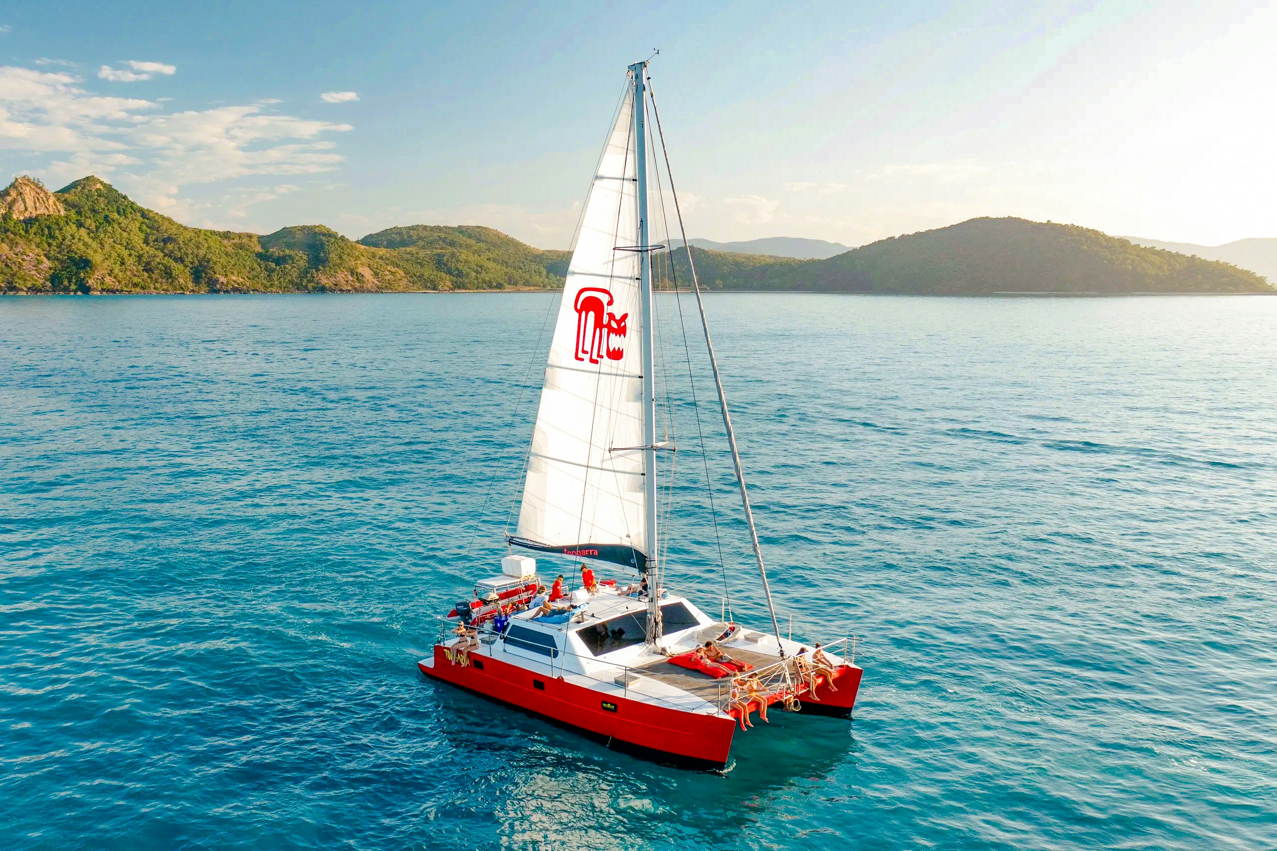 Catamaran sailing in the Whitsundays with lush islands in the background.