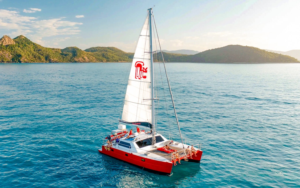 Catamaran sailing in the Whitsundays with lush islands in the background.