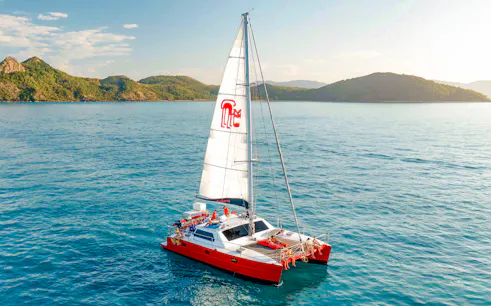 Catamaran sailing in the Whitsundays with lush islands in the background.