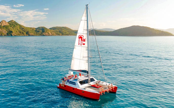Catamaran sailing in the Whitsundays with lush islands in the background.