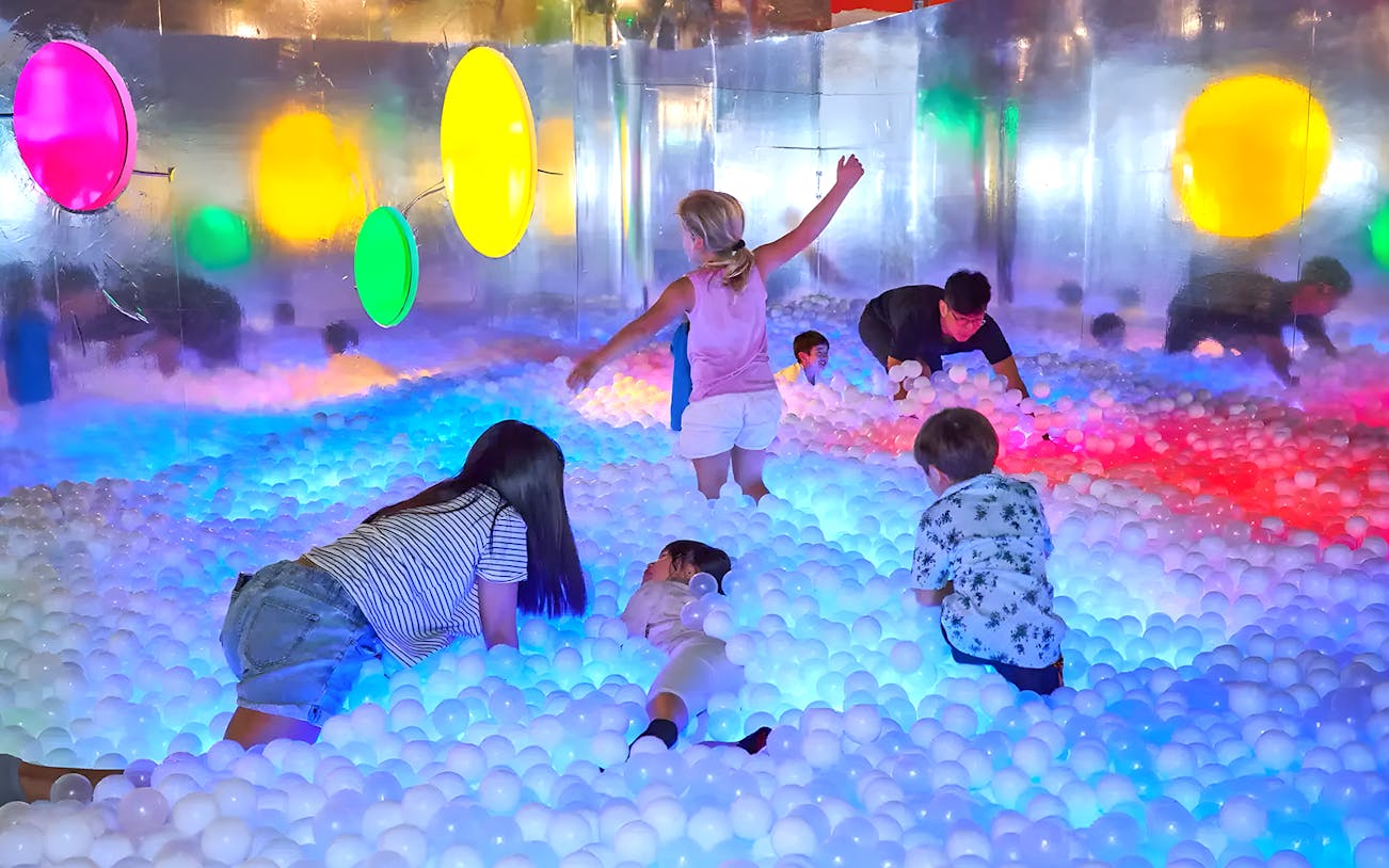 Children playing in a colorful ball pit at Chaos Lab, a creative experience.