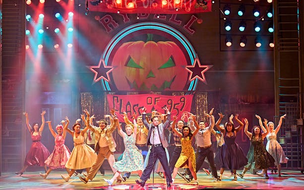 Stage performance of "Grease" with dancers in 1950s attire at Rydell High School.