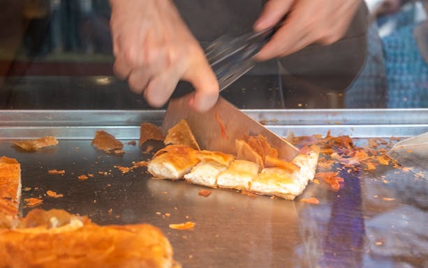 Pastry being sliced during Athens Old Town food tour.
