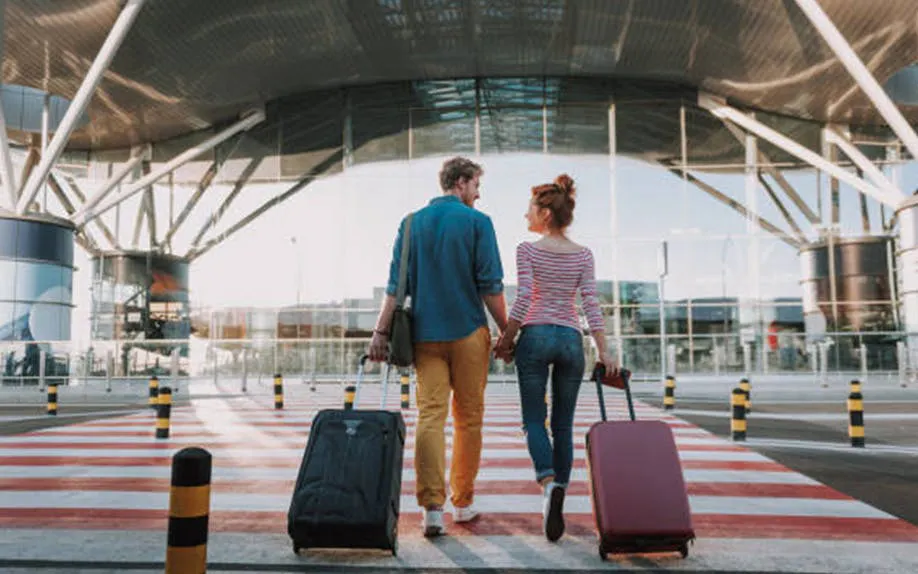 Couple with luggage walking towards airport terminal for Luxor to Hurghada transfer.