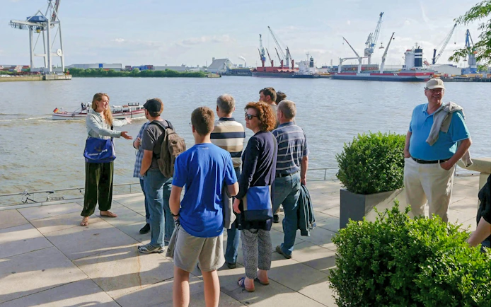 Tour guide explaining Elbphilharmonie features to a group by the Hamburg harbor.