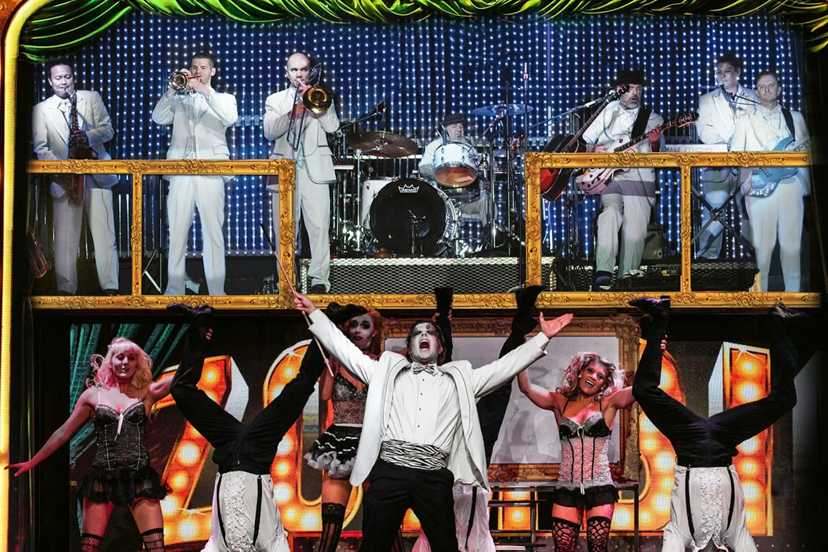 Performers in zombie-themed burlesque show with live band in background.