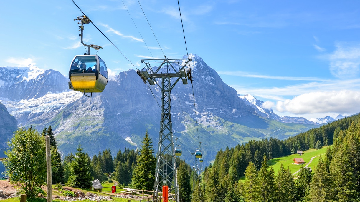 Cable car ascending in the Swiss Alps with mountain and forest views.