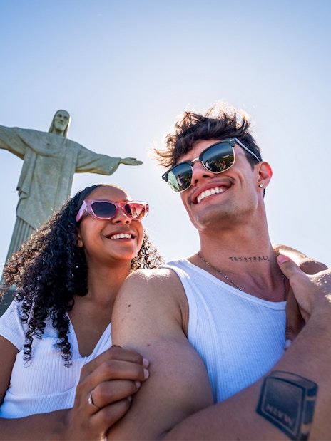 Couple smiling in front of Christ the Redeemer statue, Rio de Janeiro.