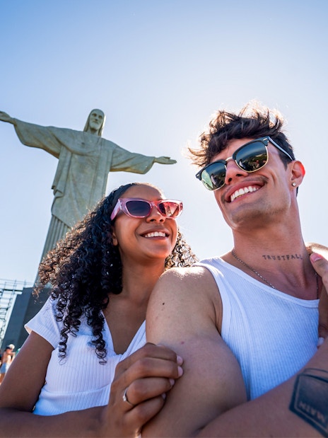 Couple smiling in front of Christ the Redeemer statue, Rio de Janeiro.