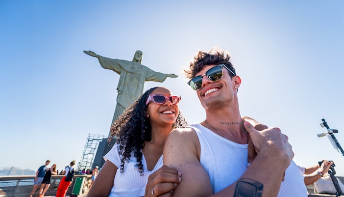 Couple smiling in front of Christ the Redeemer statue, Rio de Janeiro.