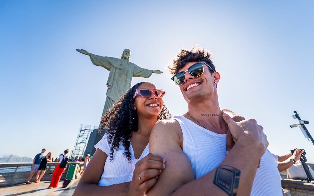 Couple smiling in front of Christ the Redeemer statue, Rio de Janeiro.