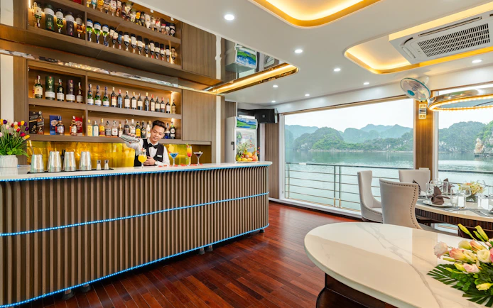 Bartender mixing drinks at Hercules premium bar with scenic view of Ha Long Bay.