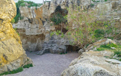 Hercules Cave entrance with rocky formations and greenery in Tangier, Morocco.