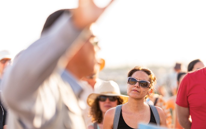 Tour guide speaking to a group of tourists outdoors.