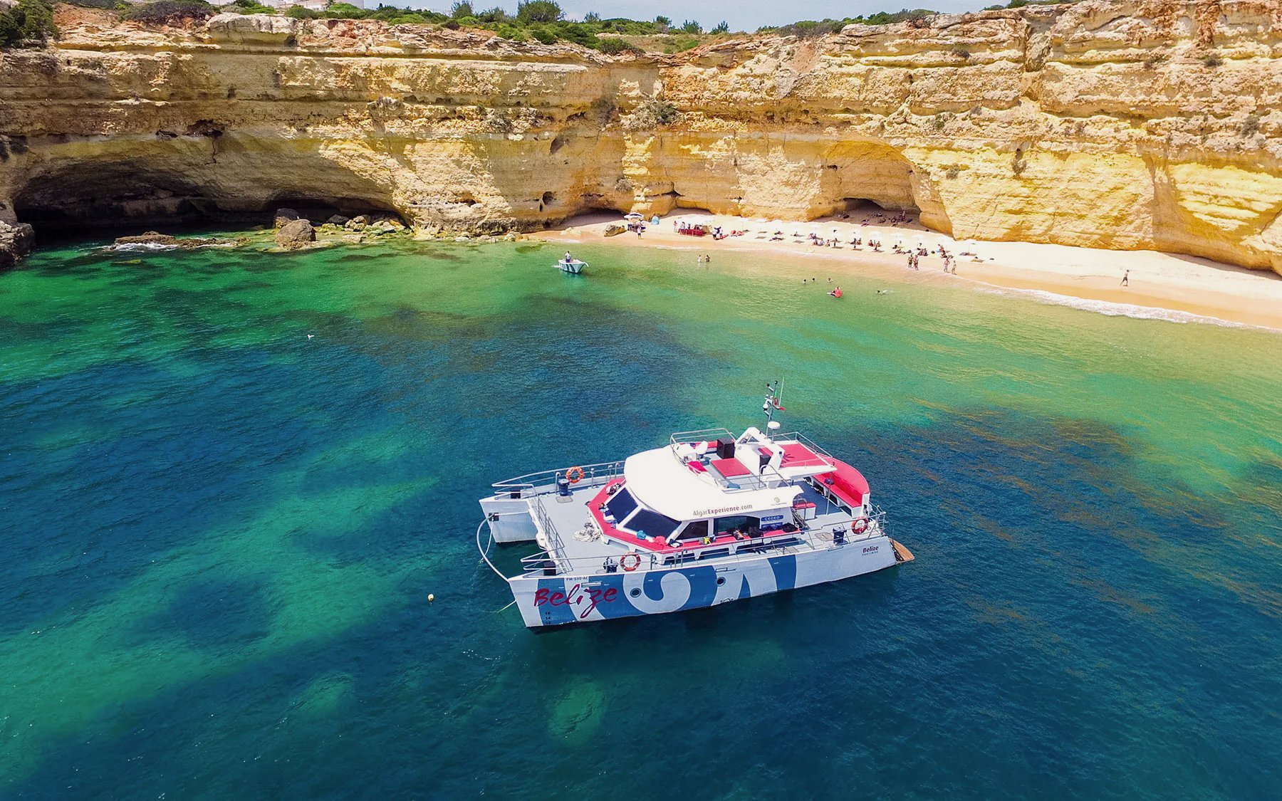 Catamaran near Benagil Cave with beach and cliffs, Albufeira cruise.
