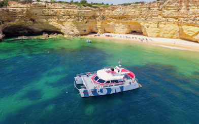 Catamaran near Benagil Cave with beach and cliffs, Albufeira cruise.