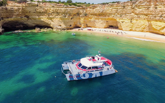 Catamaran near Benagil Cave with beach and cliffs, Albufeira cruise.